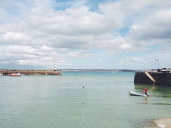 Boats in sea against cloudy sky