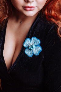 Midsection of woman wearing artificial flower pattern brooch
