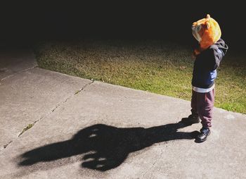 High angle view of boy standing on footpath at night