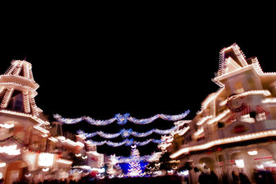 Low angle view of illuminated carousel against sky at night