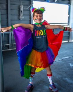 Portrait of cheerful girl wearing colorful costume while standing against wall