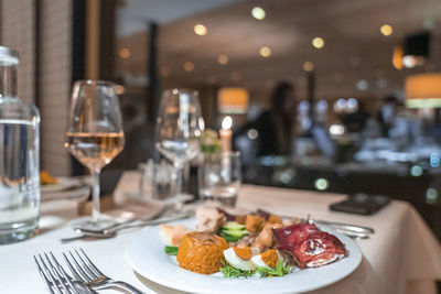 Close-up of delicious meal served in plate by wineglass on dining table at hotel