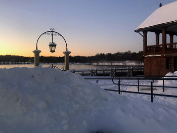 Snow covered land against sky during sunset