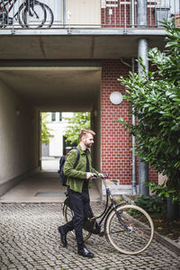 Male entrepreneur with bicycle walking on footpath