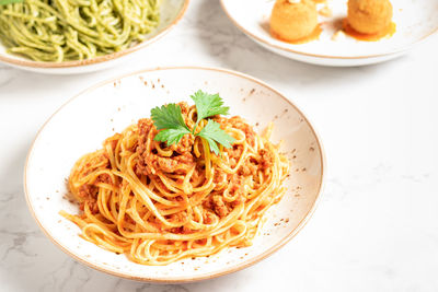 Delicious dishes of italian gastronomy on white marbled board and gray background. pasta bolognese