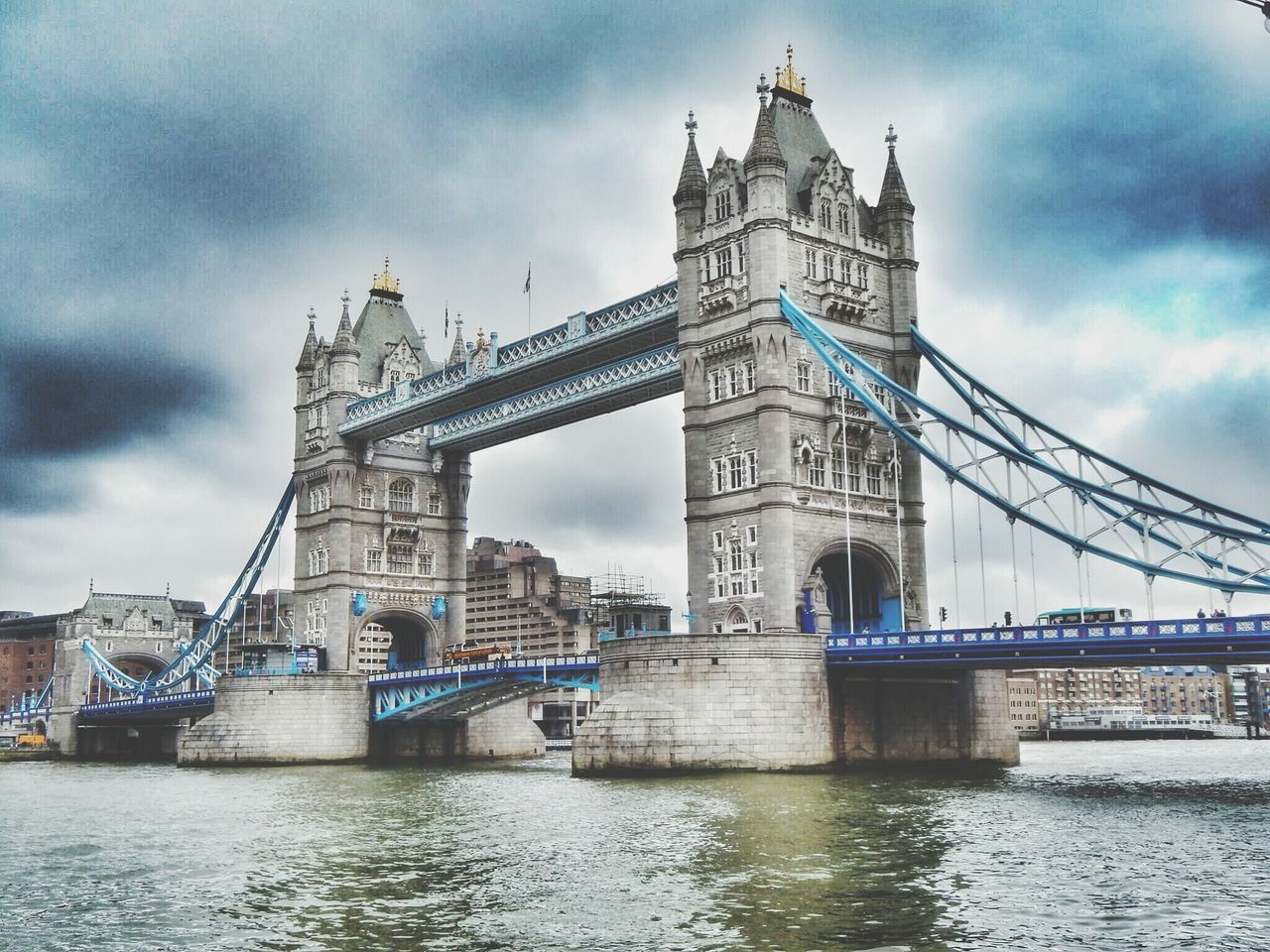 architecture, built structure, bridge - man made structure, connection, sky, building exterior, river, water, cloud - sky, waterfront, city, famous place, bridge, engineering, travel destinations, international landmark, transportation, capital cities, cloudy, low angle view