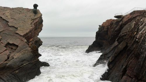 Scenic view of sea by cliff against sky