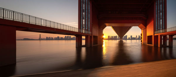 Bridge over river in city at sunset