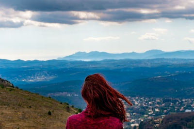 Rear view of woman looking at mountains against sky