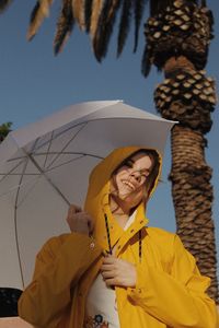 Portrait of woman with umbrella against sky