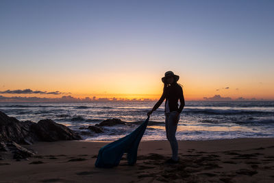 Silhouette of young girl with hat at sunset on cotillo beach, fuerteventura, canary islands.