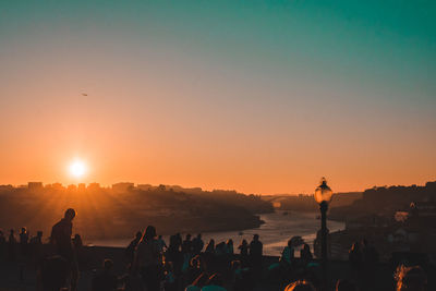 Silhouette people standing on beach against sky during sunset