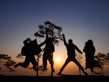 Silhouette people jumping against clear sky during sunset