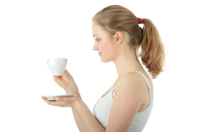 Side view of woman holding coffee cup against white background