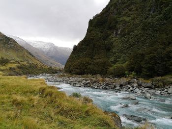 Scenic view of river stream amidst mountains against sky