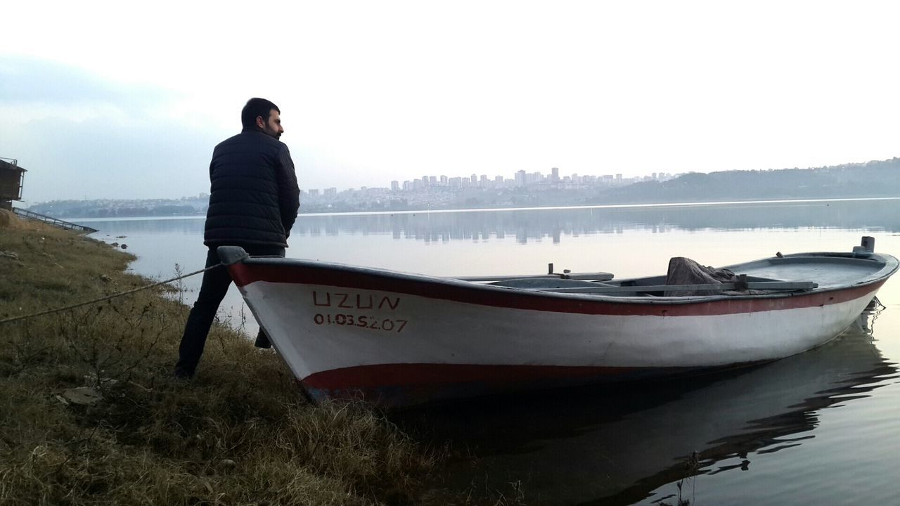 water, nautical vessel, boat, transportation, mode of transport, lifestyles, lake, men, sky, leisure activity, rear view, nature, tranquility, moored, casual clothing, tranquil scene, reflection, standing