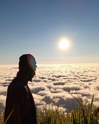 Man standing on field against sky during sunset