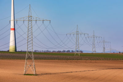 Electricity pylons dominate the rural landscape with a huge wind turbine tower