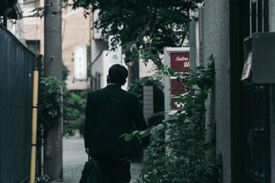 Rear view of a man walking amidst buildings