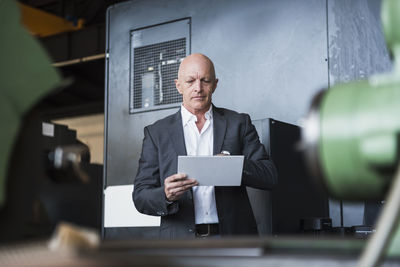 Man with tablet at machine on factory shop floor