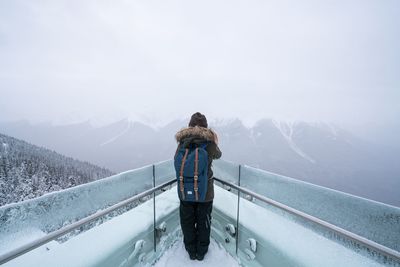 Rear view of man standing on snow covered mountain