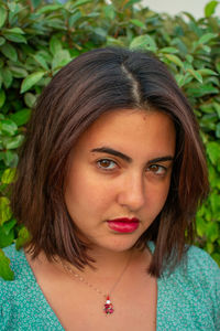 Close-up portrait of beautiful young woman by plants