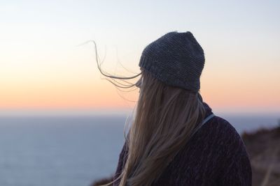 Rear view of woman standing against sea during sunset