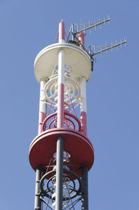 Low angle view of communications tower against clear blue sky