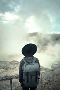 Rear view of man standing on land against sky