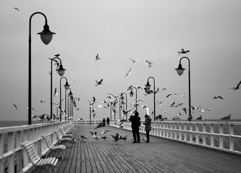 People on pier against sky