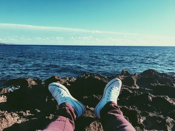 Low section of man at beach against sky