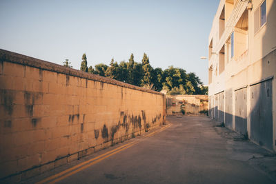 Empty road amidst buildings against clear sky