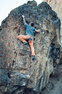 Male climber is reaching the next hold on the boulder in smith rock
