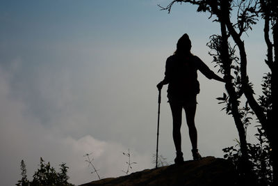 Low angle view of silhouette woman hiking on mountain against sky