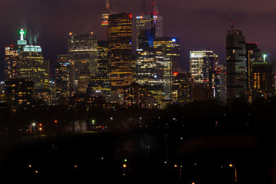 Illuminated cityscape against sky at night