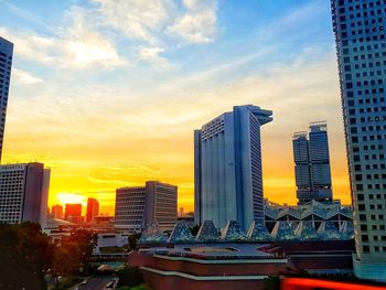 Modern buildings in city against sky during sunset
