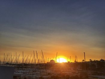 Silhouette sailboats on shore against sky during sunset