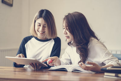 Young woman using phone while sitting on table