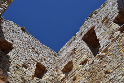 Low angle view of old building against blue sky