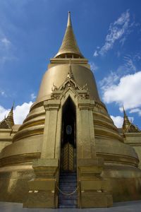 Low angle view of gold stupa temple building against sky