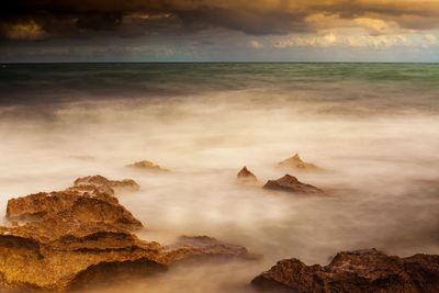 Rocks on sea shore against sky