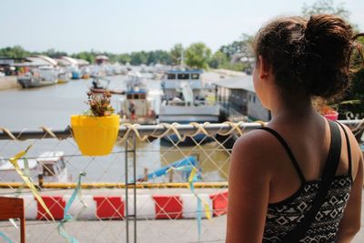 Rear view of girl standing at harbor in city