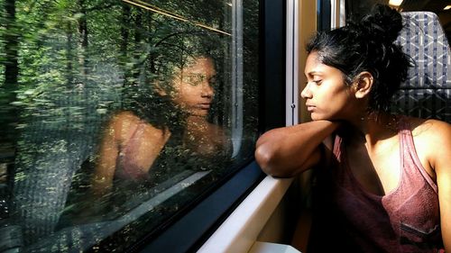 Young woman looking through window while sitting in train