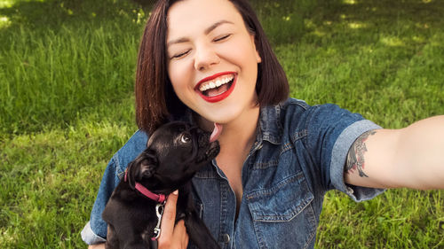 Portrait of young woman with dog on field