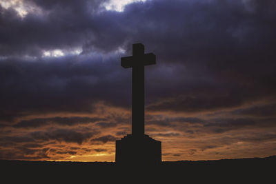 Low angle view of silhouette cross against dramatic sky