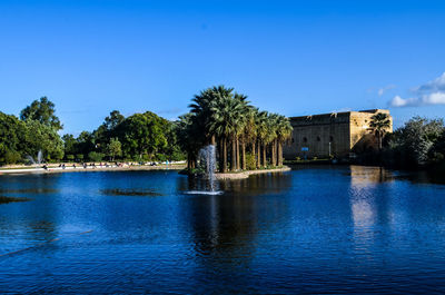 Scenic view of lake by building against clear blue sky