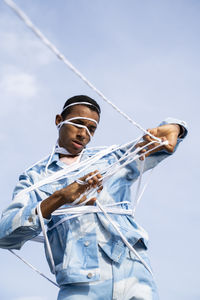 Trapped man removing rope while standing against sky