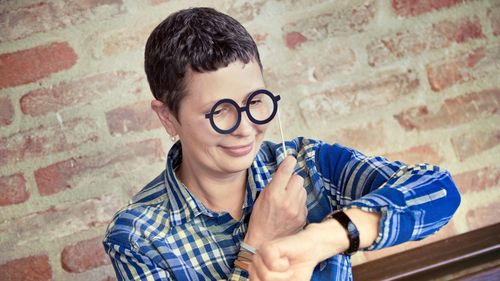 Woman checking time through novelty glasses against brick wall