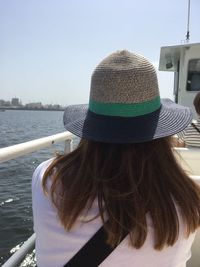 Rear view of woman in hat against boat