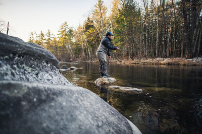 A man fly-fishes during a fall morning on a maine river